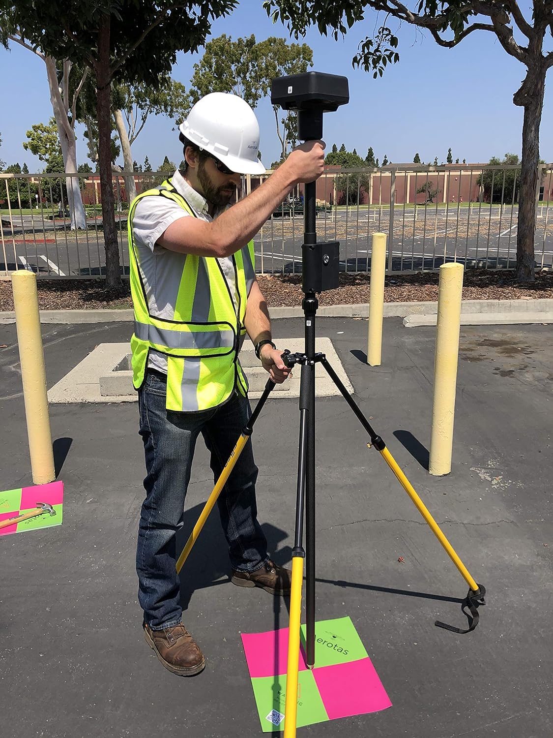 Surveyor setting up independent checkpoints on a paved site.